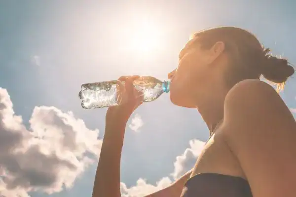 Image of woman drinking water to hydrate Arundel after run.