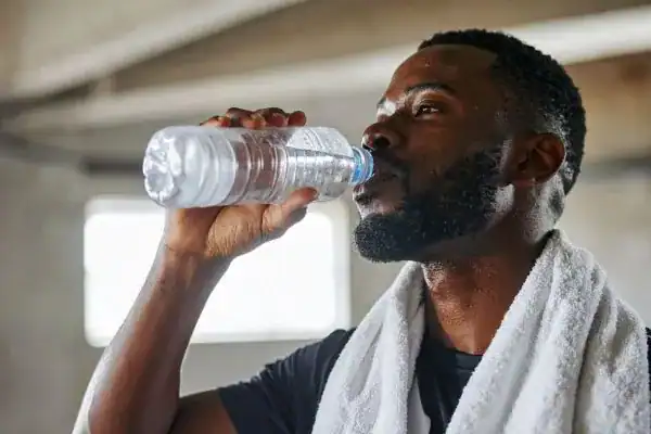 Image of man drinking water to improve hydration Arundel after work out.